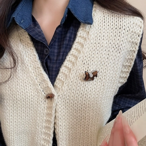Detail of a vintage rocking horse brooch with tiger eye texture on a knitted vest