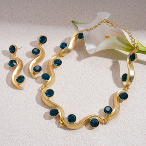 Retro gold jewelry set with dark blue crystals and wave patterns on a textured surface