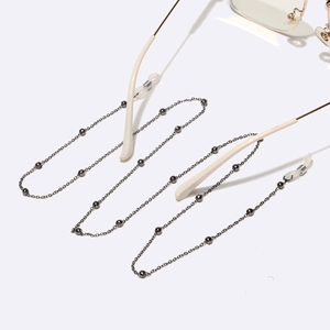 Gunmetal beaded eyewear chain on light beige glasses in a macro top view