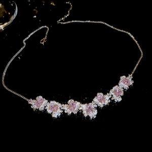 Close-up of pink zircon flower pendant necklace with shimmering crystals on black background