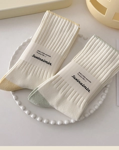 Detail of knit cotton mid-tube socks with contrast toe design on a white ceramic plate