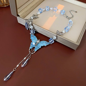 Détail d'un collier papillon bleu avec perles et gouttes de cristal dans un écrin bijou