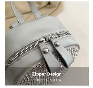 Close-up of silver-grey bag showing two-way metal zippers and rhinestone details