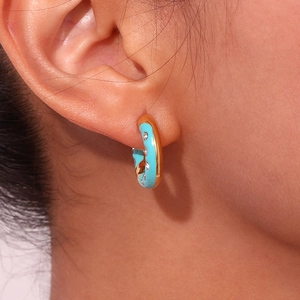 Close-up of gold-plated hoop earring with sky blue enamel and sparkling small crystals