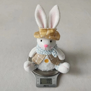 Detail shot of a plush Easter bunny doll with plaid vest and hat on a digital scale