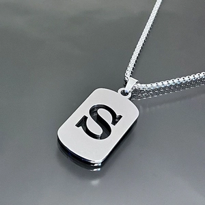 Macro view of silver stainless steel box chain necklace with hollow letter S pendant