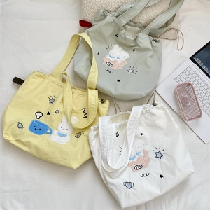 Dettaglio della borsa tote in tela ricamata con chiusura a coulisse in tre colori pastello