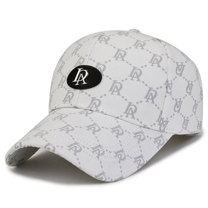 White baseball cap with grey logo pattern and black oval metal emblem from a side view