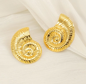 Macro detail of 18K gold plated conch spiral earrings with fine texture on white silk