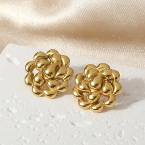 Elegant gold hollow swirl floral stainless steel earrings on white stone display