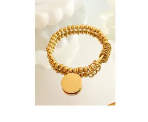 Close-up of golden beaded bracelet with engraved LOVE TODAY pendant on a mirror