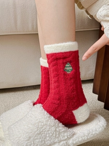 Close-up of thick red Christmas socks with green tree embroidery and plush white lining