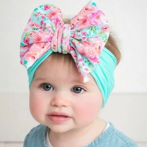 Detail of floral printed bow on a stretchy mint green nylon headband for baby girls