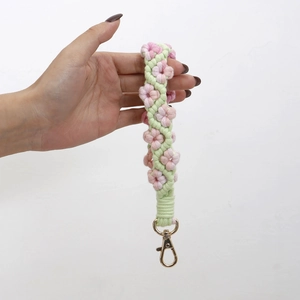 Detail of handmade woven floral keychain with pink flowers and gold lobster clasp