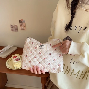 Detail of quilted floral makeup bag with pink flower pattern and woven label