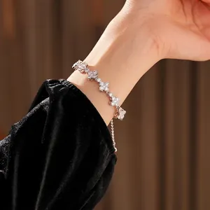 Sparkling zircon clover link bracelet in silver finish worn on woman's wrist