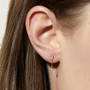 Detail of s925 gold earring featuring a pear-cut zircon and white opal stone on ear