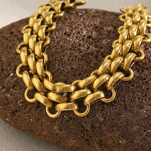 Macro shot of 18K gold plated triple layered chunky chain bracelet on a brown rock