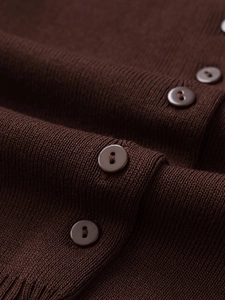 Macro shot of dark brown knit cardigan texture with matching four-hole buttons detail