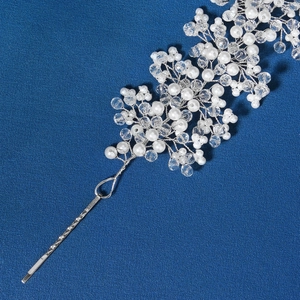 Detailed close-up of bridal hair comb with white pearls and clear crystals on blue texture