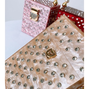 Macro detail of acrylic evening clutch featuring marble texture and sparkling rhinestones