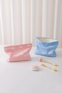 Dettaglio di trousse rosa e blu con stampe a fiocco e texture a rombi goffrati