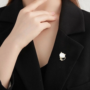 Detailed view of a golden cat brooch with opal gem and diamonds on a black suit lapel