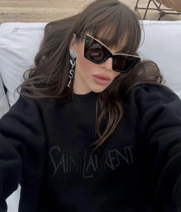 Detail of classic black oversized cat-eye sunglasses with luxury brand logo sweatshirt