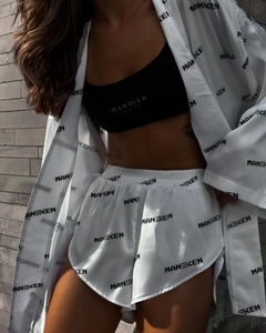 Detail of white silk satin loungewear set featuring contrast MANEKEN brand logo prints