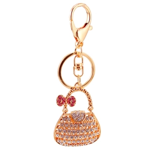 Golden handbag keychain with clear crystals and pink rhinestone bow on white background