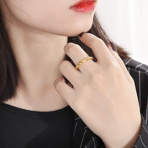 Close-up of a minimalist golden twisted rope ring on a finger with soft lighting