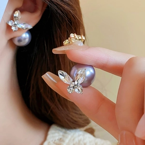 Gros plan de boucles d'oreilles papillon dorées avec perles violettes portées à l'oreille