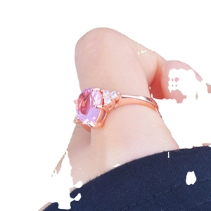 Rose gold ring with pear-cut pink diamond center stone on hand in white background