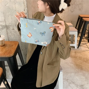 Close-up of light blue canvas makeup bag with exquisite butterfly embroidery and zip closure