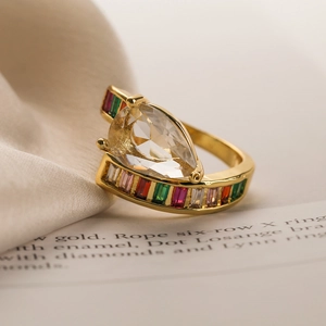 Macro detail of 18K gold ring with pear-cut main stone and multicolor side gems
