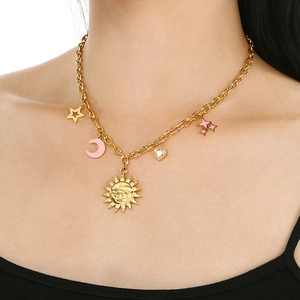 Detail shot of a gold necklace with sun, pink moon, stars, and heart pendants on model