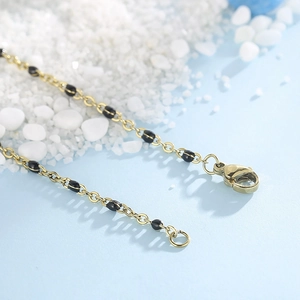 Detail of gold titanium steel necklace with black beads and a sturdy lobster clasp