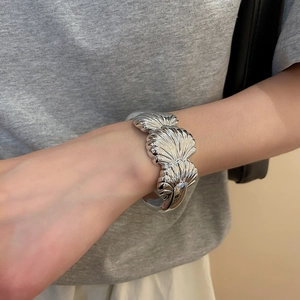 Detailed view of silver shell-shaped cuff bracelet with 3D embossed metallic texture