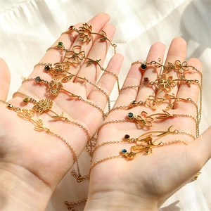 Golden stainless steel birth flower bracelets with colorful gemstones held in palm