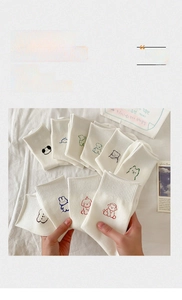 Close-up of white cotton socks featuring colorful cartoon animal embroidery and ribbed cuffs