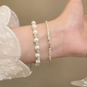 Close-up of elegant layered pearl bracelet and silver bead hand chain on a wrist