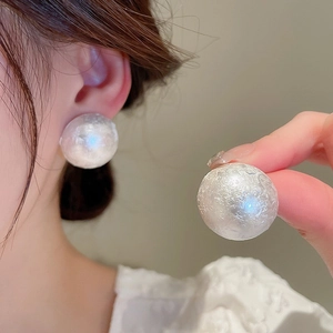 Elegant gold-plated hook earrings featuring large white baroque pearls on model's ear