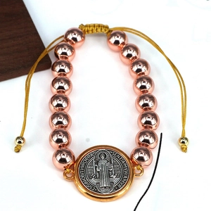 Detailed macro view of St. Benedict medal and tricolor beads on woven religious bracelet