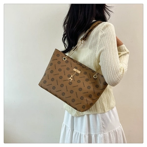 Brown monogram tote bag detail showing the gold deer charm and chain leather strap