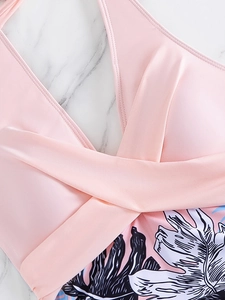 Detail of pink halter bikini top featuring twist knot design and tropical leaf prints