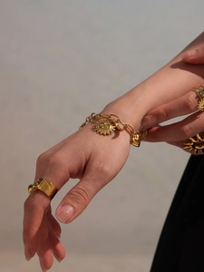 Detail von 18k vergoldetem Sonnen- und Herzanhänger an einem klobigen Armband