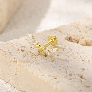 Close-up of golden curved leaf labret stud with sparkling marquise-cut zircon crystals