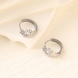 Macro detail of silver geometric hoop earrings with sparkling cubic zirconia on a white wave