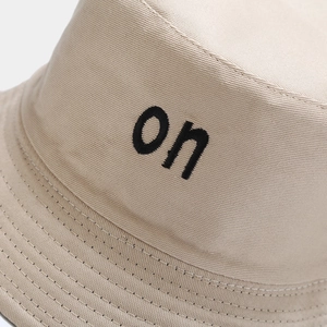 Gros plan de la broderie noire et coutures soignées sur un chapeau bob en toile beige