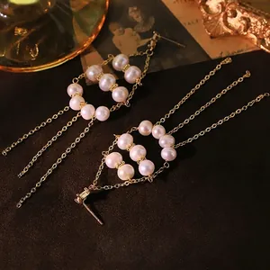 Elegant natural pearl drop earrings with long gold tassels on a vintage fabric background